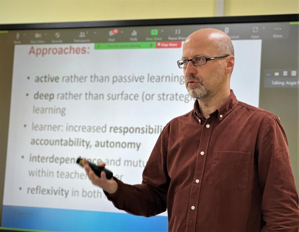 A lecturer standing in front of a powerpoint presentation